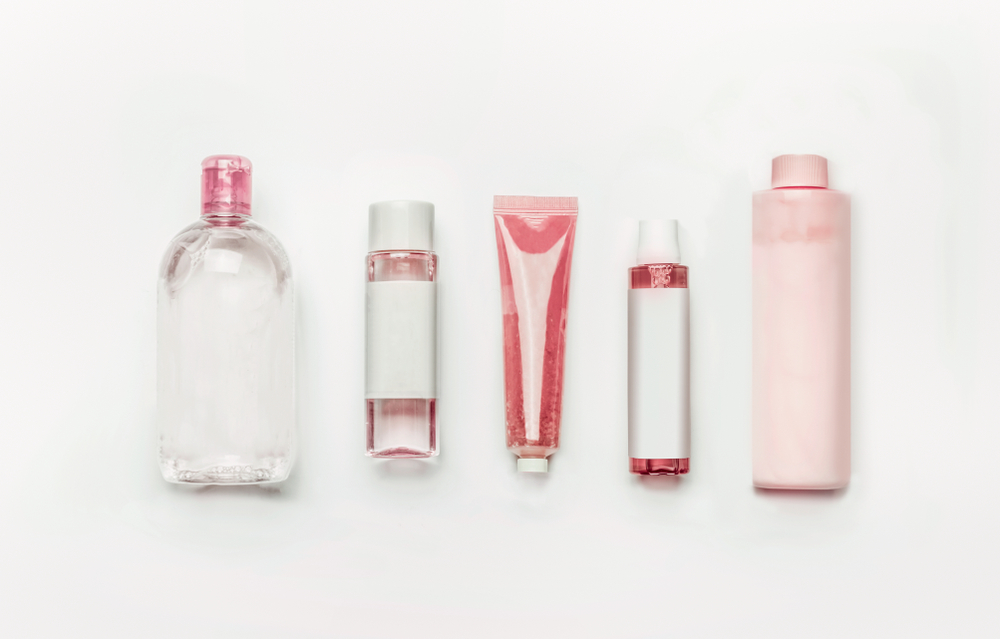 2 Pink natural cosmetic products gel, lotion, serum, micellar water and toner, bottles and tubes with branding mock up on white desk background , top view, flat lay . Facial s